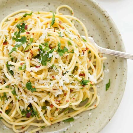 Spaghetti with garlic and olive oil on a grey plate.