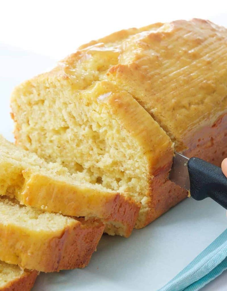 A knife cutting a healthy yogurt cake into slices over a white background.