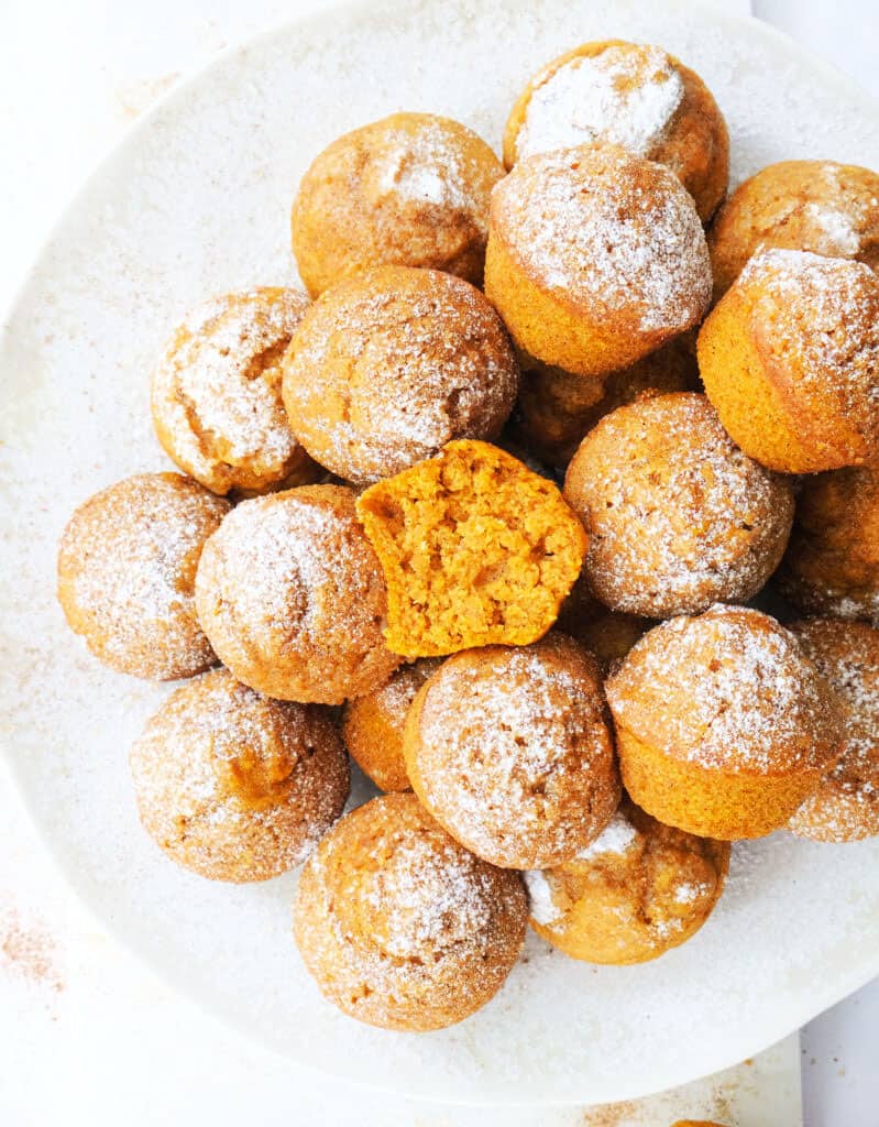Top view of mini pumpkin muffins on a white plate.