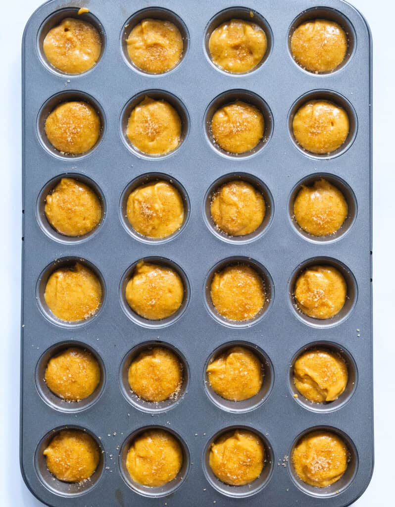 Top view of a muffin tray filled whit pumpkin batter before baking.