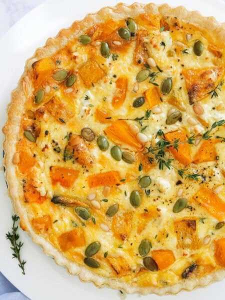 Top view of a pumpkin quiche over a white background.