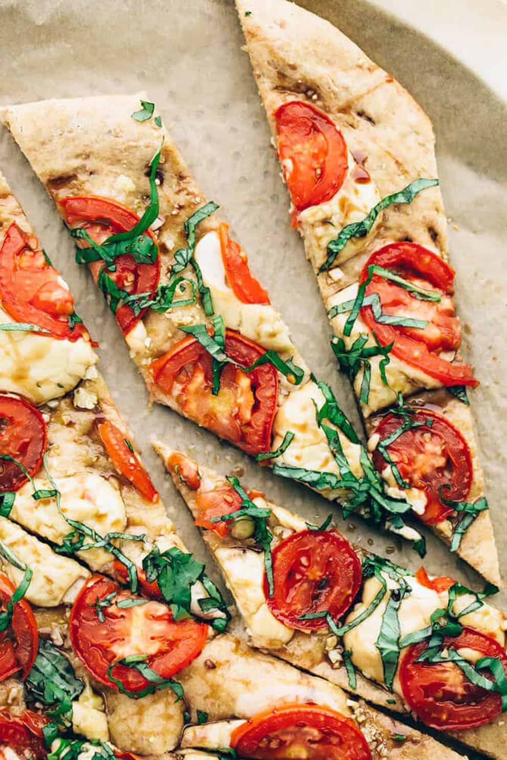 Slices of vegan caprese pizza on parchment paper - Blissful Basil