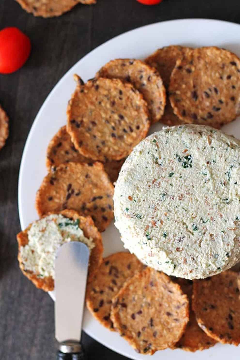 Vegan almond cheese spread with round crackers on a white plate - Delightful Adventures