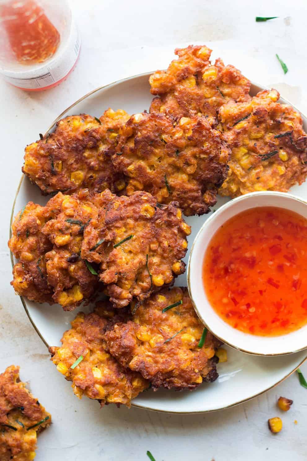 Vegan thai corn fritters on a white round plate with a red dipping sauce - Lazy Cat Kitchen