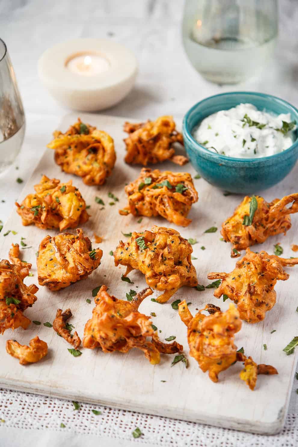 Vegan shallot bhajis with minted yogurt on a white board - UK shallots