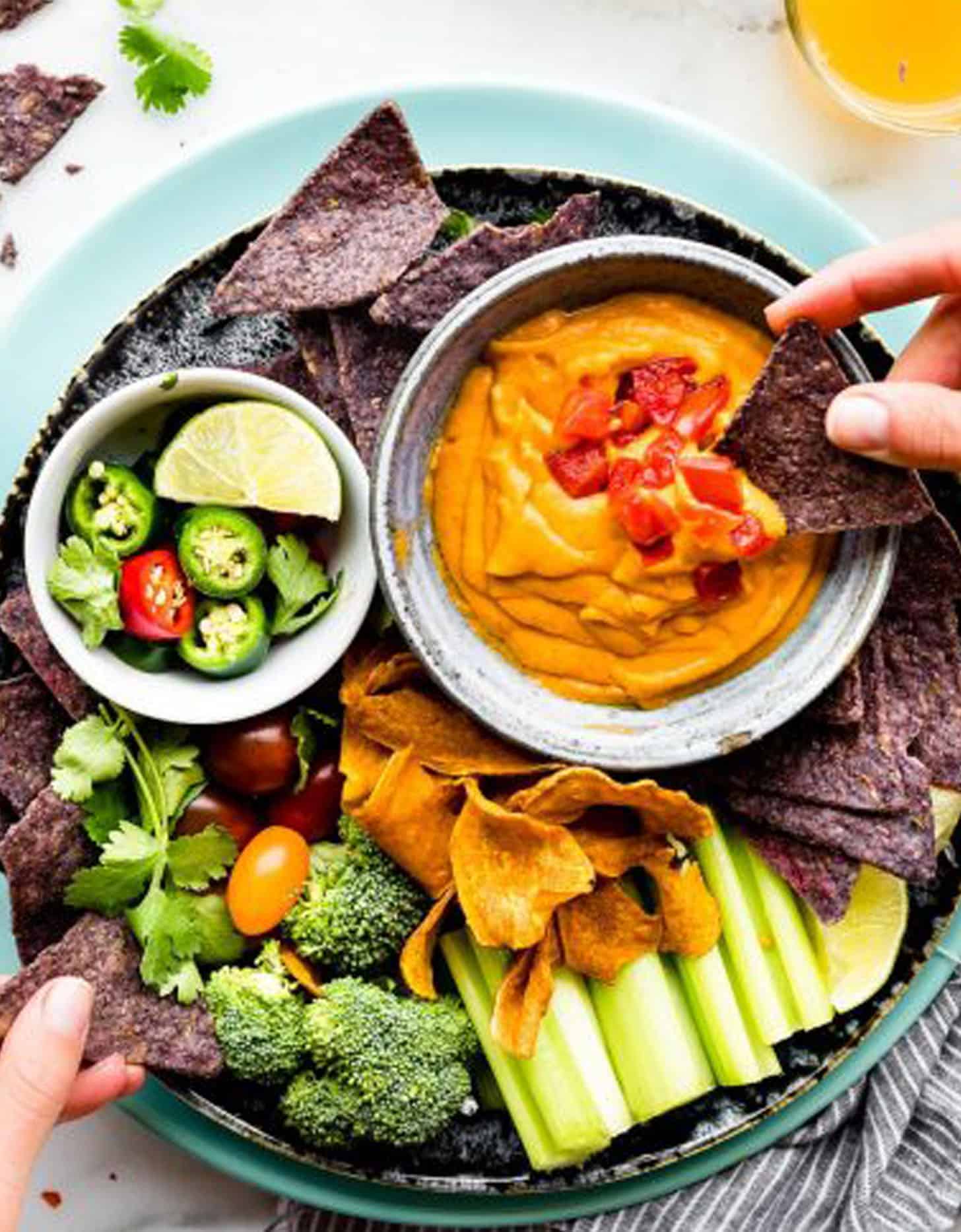 Vegan salsa con queso in a bowl served with raw vegetables and tortilla chips - by Cotter Crunch