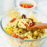 A glass bowl full of couscous salad with chickpeas.