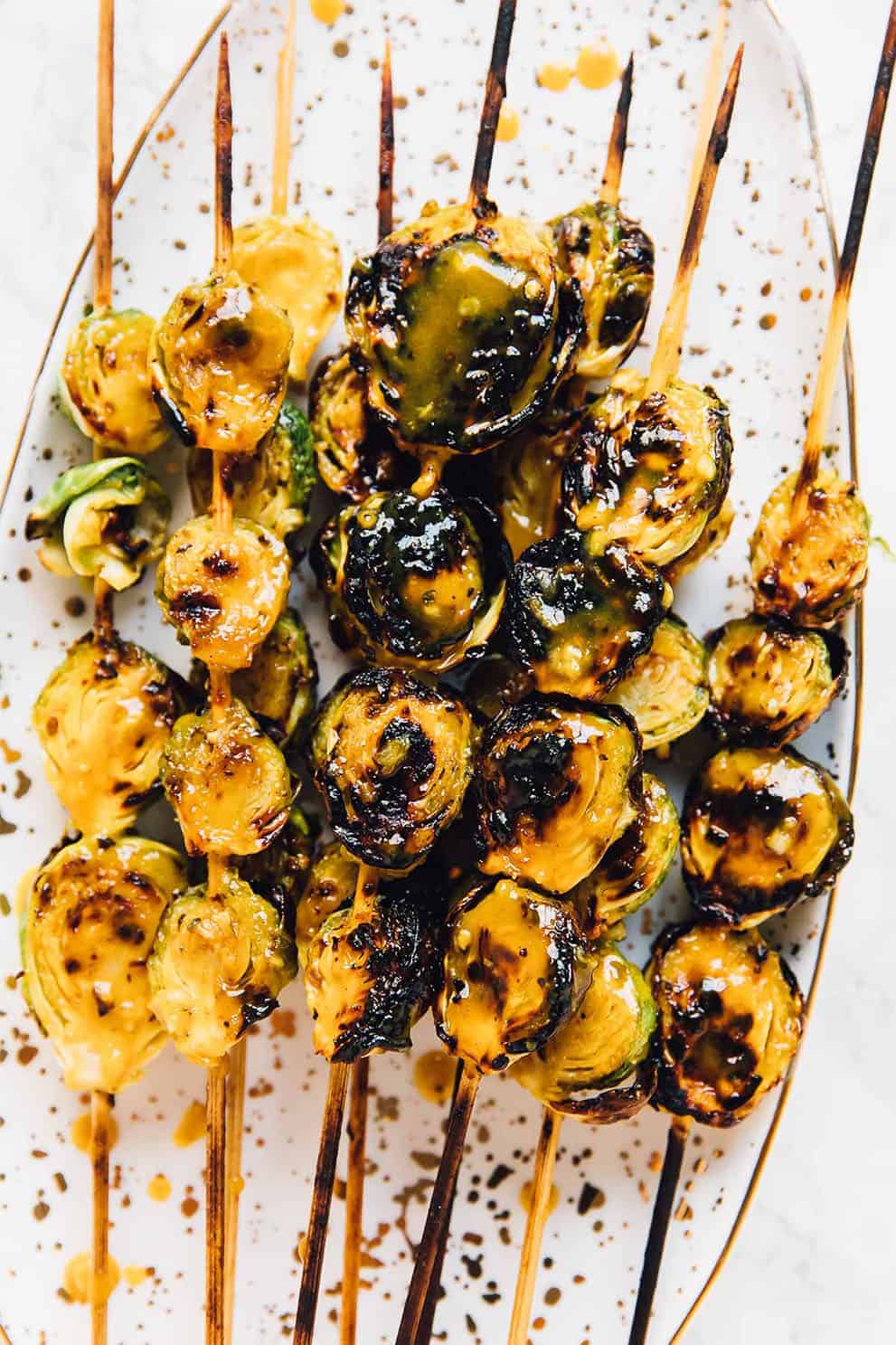 Skewers of grilled brussels sprouts on an oval white tray - Jessica in the Kitchen