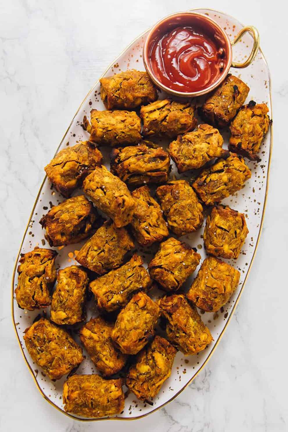 Sweet potato tater tots with red dipping sauce on an oval serving plate - Jessica in the kitchen