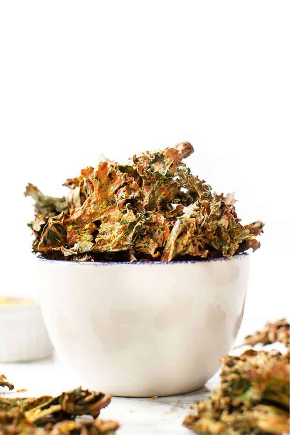 Vegan nacho kale chips in a white bowl over a white background - Simply Quinoa