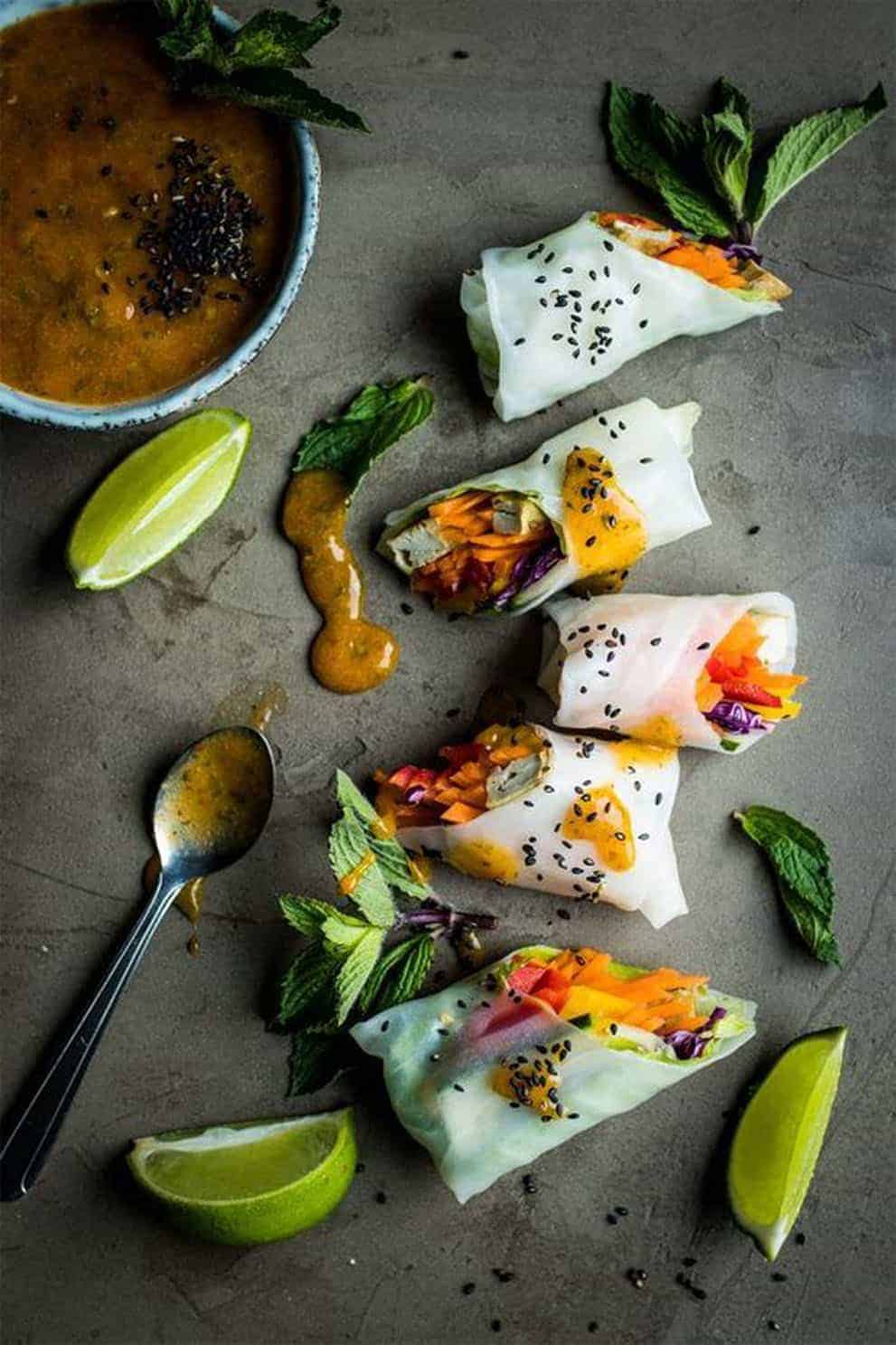 Five vegan summer rolls with dipping sauce over a grey background - Lauren Caris Cooks