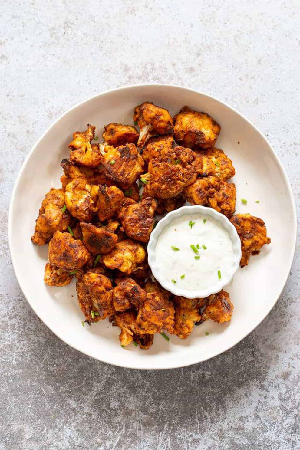 Vegan cauliflower bites in a white plate with a white dipping sauce - Vegan Richa