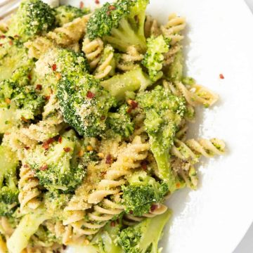 Broccoli pasta with toasted breadcrumbs on a white plate.