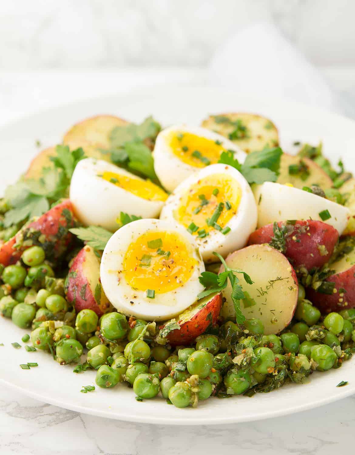 This is a delicious potato and egg salad with peas super easy to throw together, you need just a few basic and inexpensive ingredients like potatoes, eggs, frozen peas and fresh herbs.  And not only is it perfect for a picnic, but it makes a nice and healthy lunch all year round.