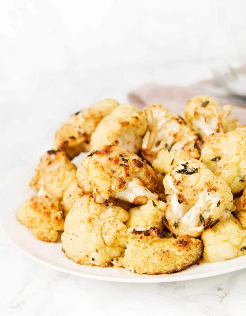 Roasted balsamic cauliflower florets on a plate over a white background.
