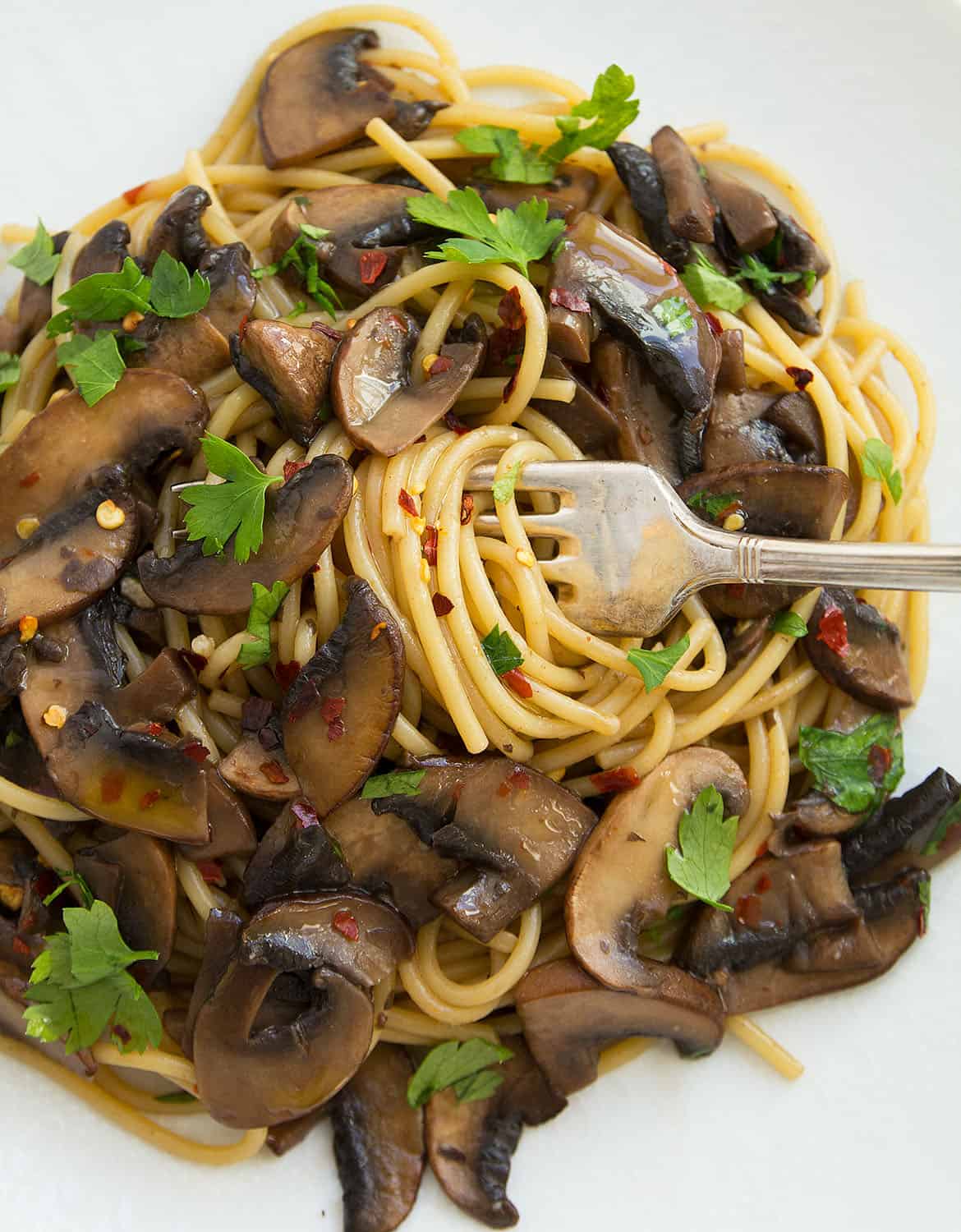 A fork is twirling the garlic mushroom spaghetti.