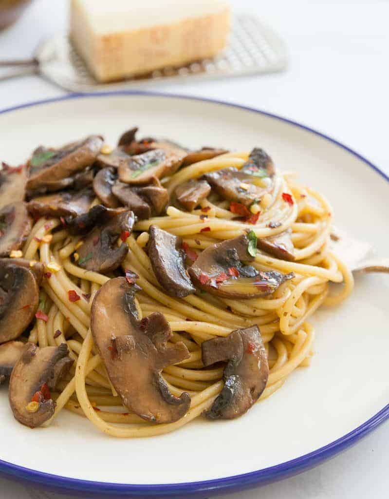 Garlic mushroom pasta on a white plate with a fork.