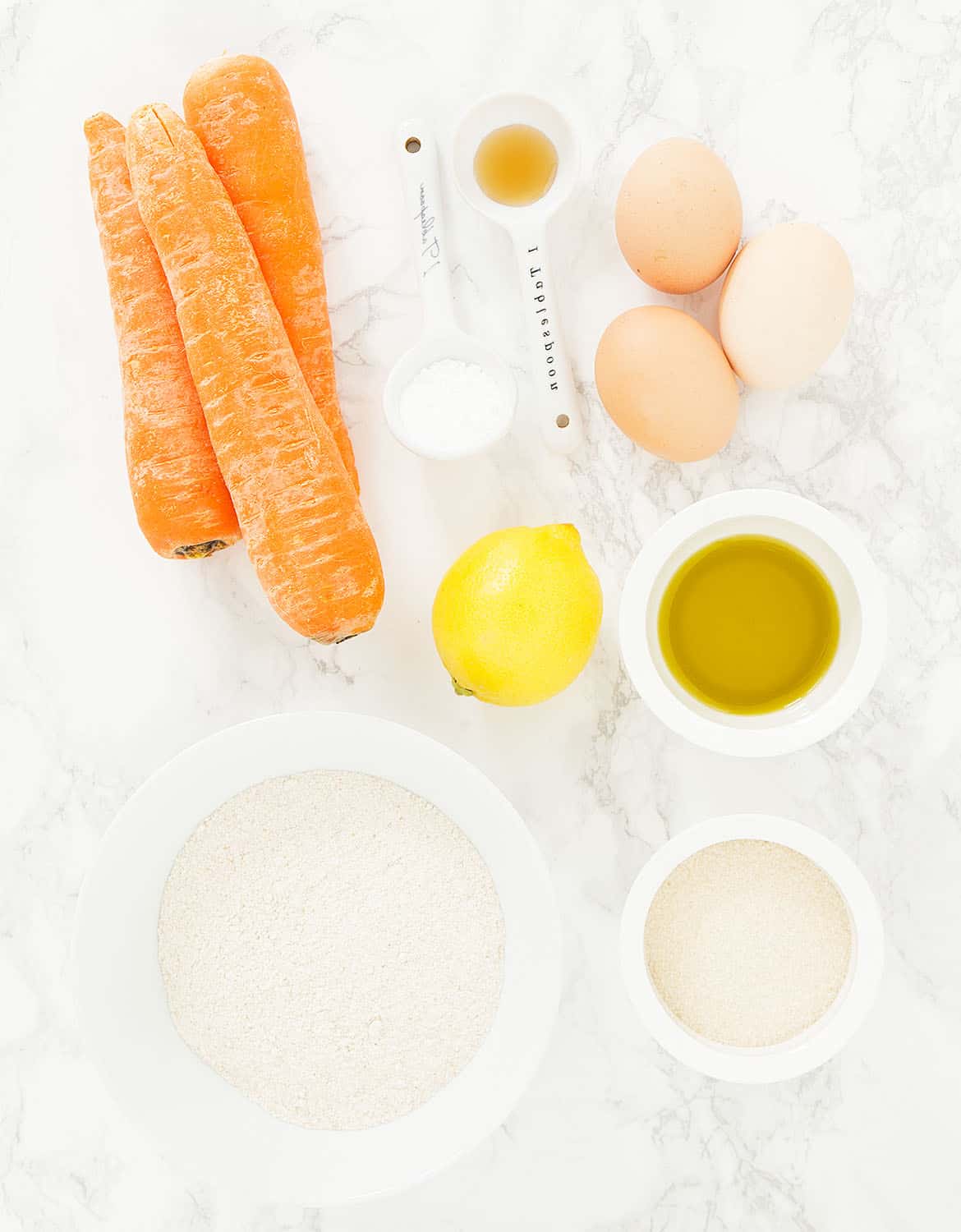 The ingredients for this healthy carrot cake are arranged over a white background.