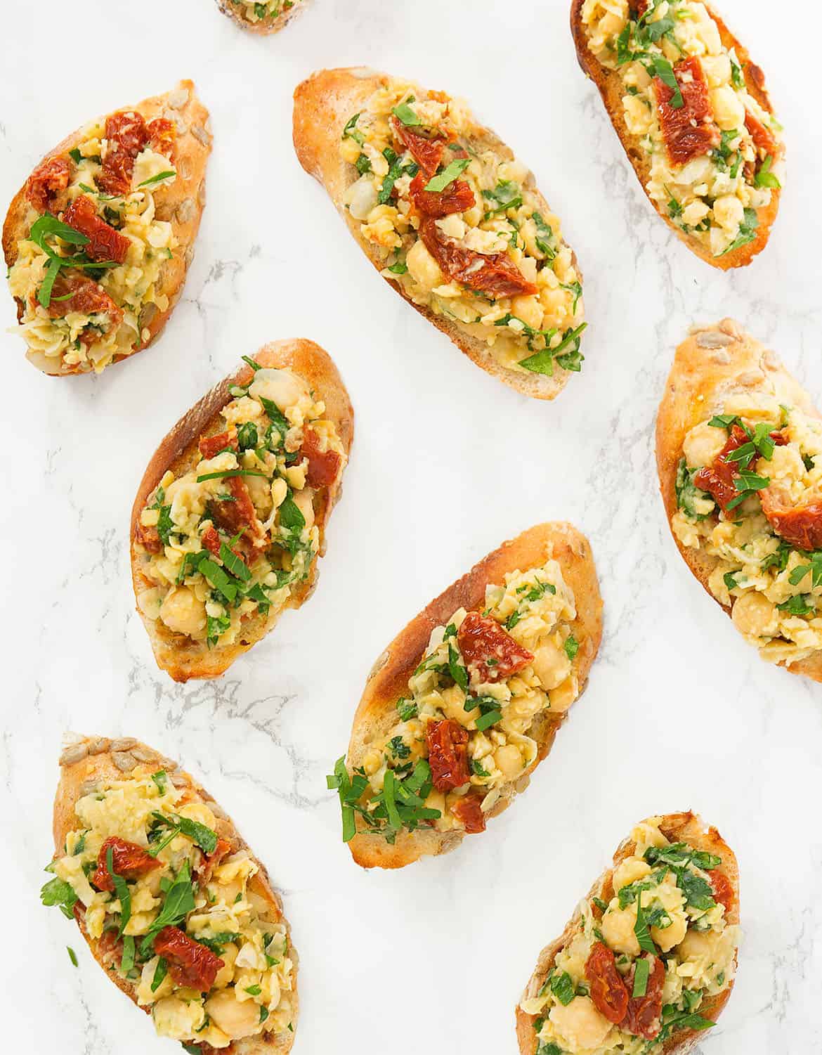 Top view of vegan chickpea bruschetta over a white background.