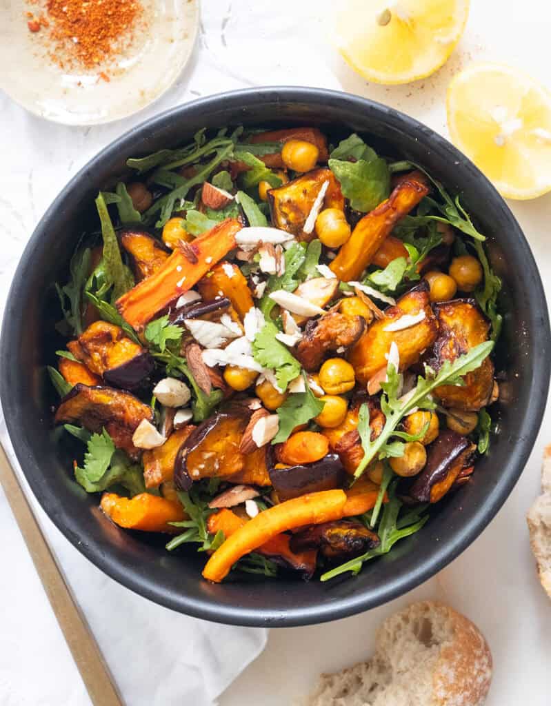 Harissa eggplant salad with carrots and chickpeas in a black bowl.
