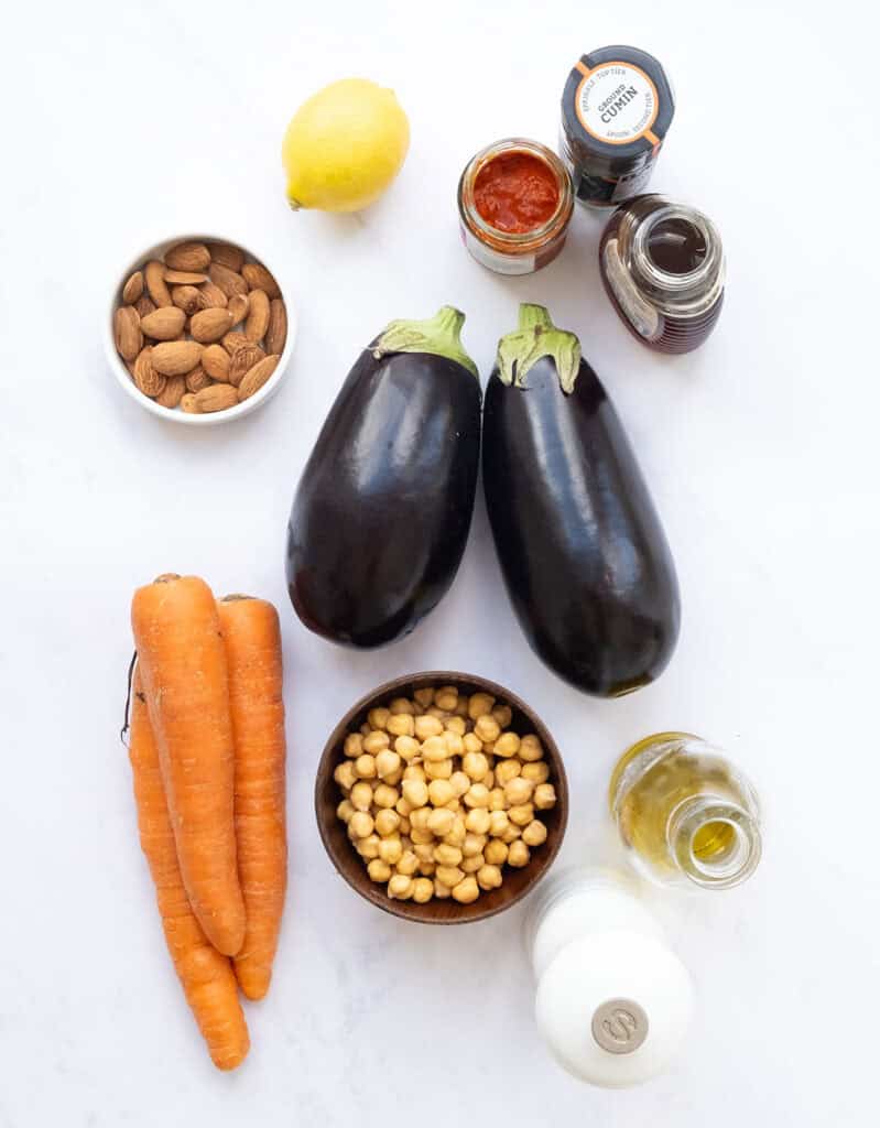 The ingredients for the sheet pan harissa eggplant and carrot salad are arranged over a white background.