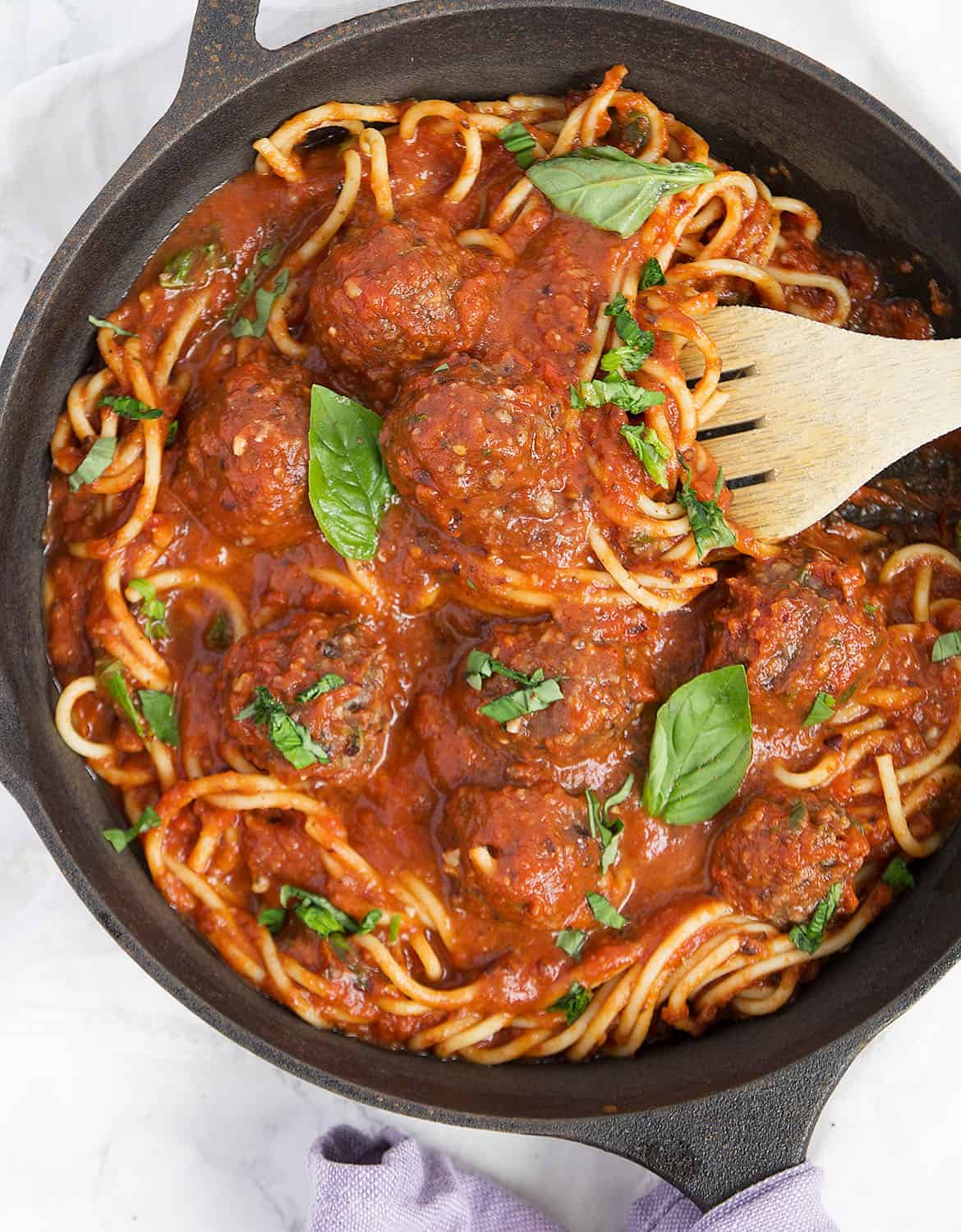 Vegan meatless meatballs with spaghetti in a cast iron skillet.