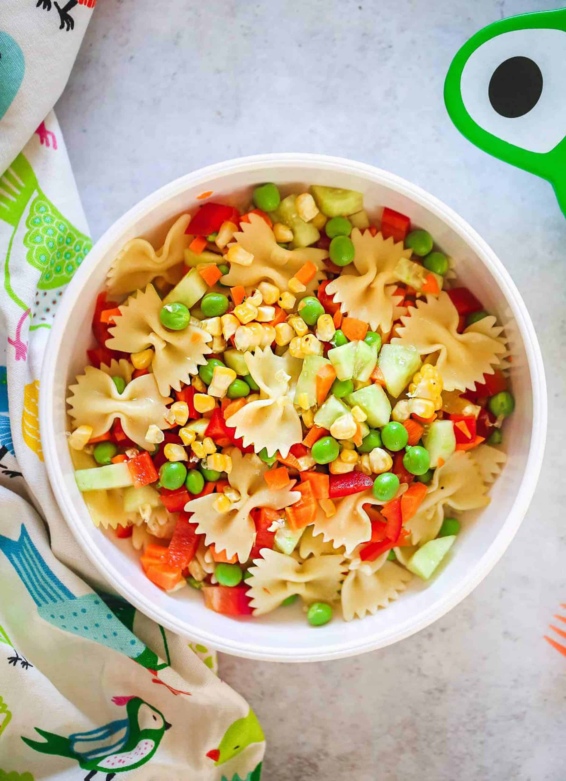 Top view of a white bowl full of pasta, peas and diced vegetables - Little Sunny Kitchen.