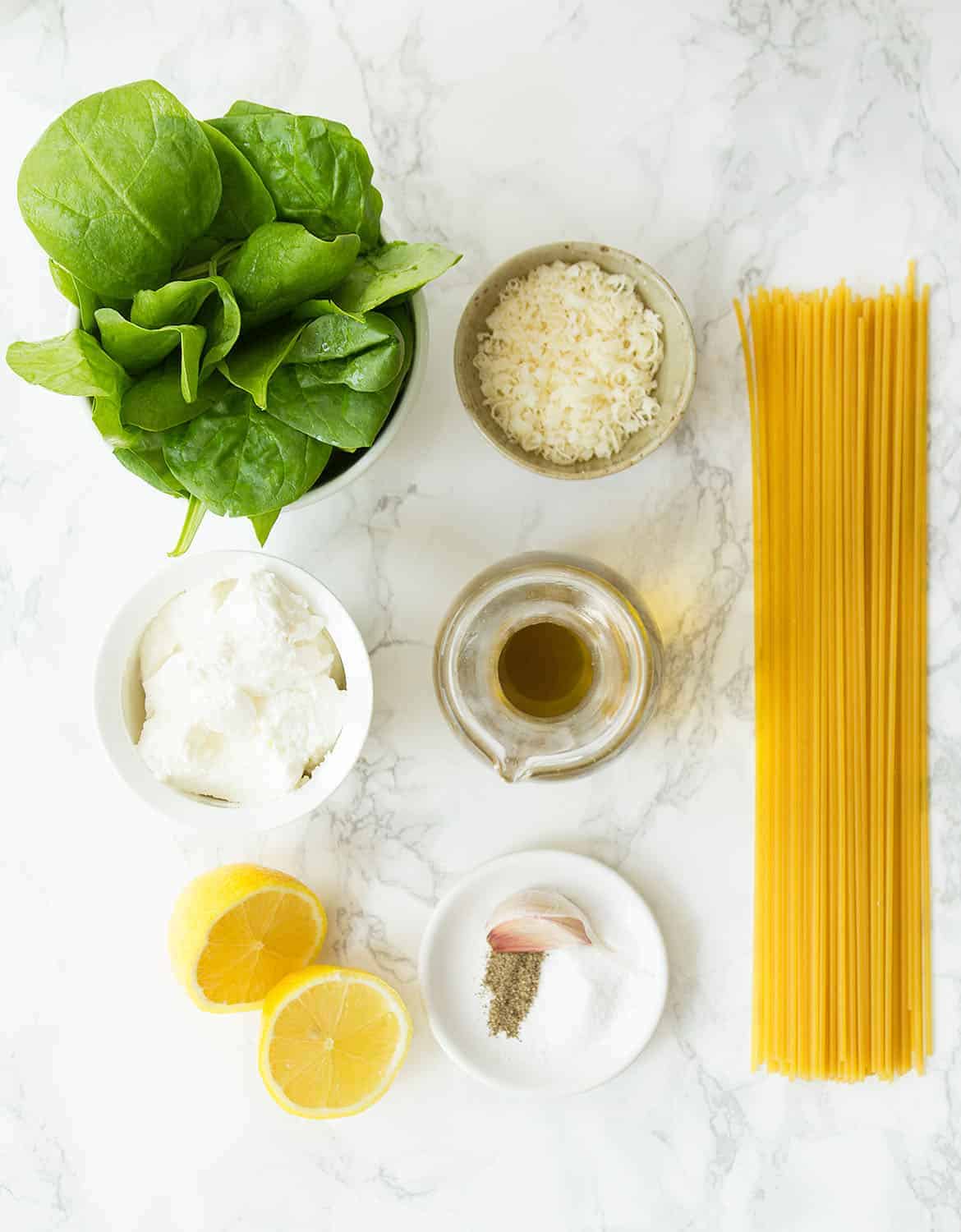 The ingredients for this lemon ricotta pasta are arranged on a white marble table.