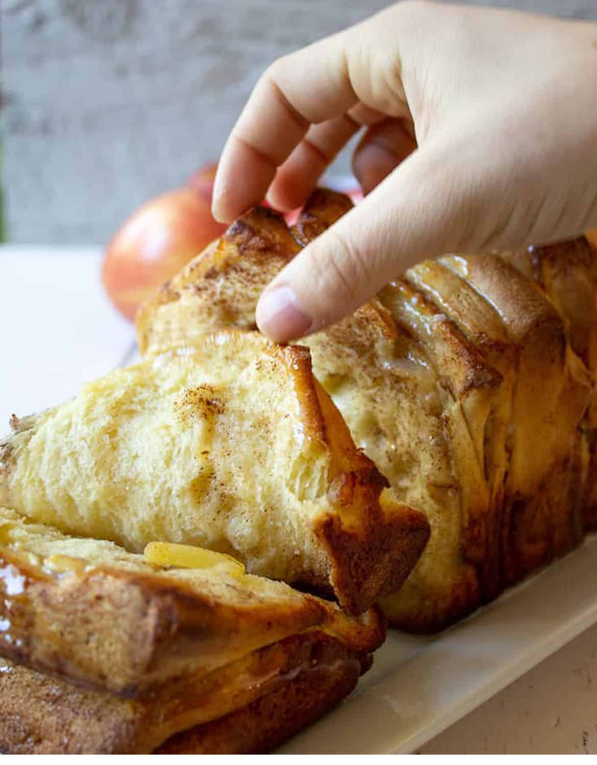 A hand taking a slice of apple pull apart bread - Beyond The Chicken Coop