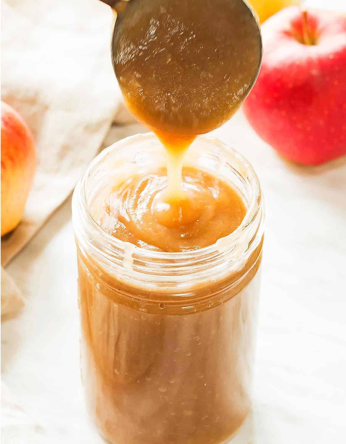 A spoon pouring apple sauce in a glass jar - Leelalicious