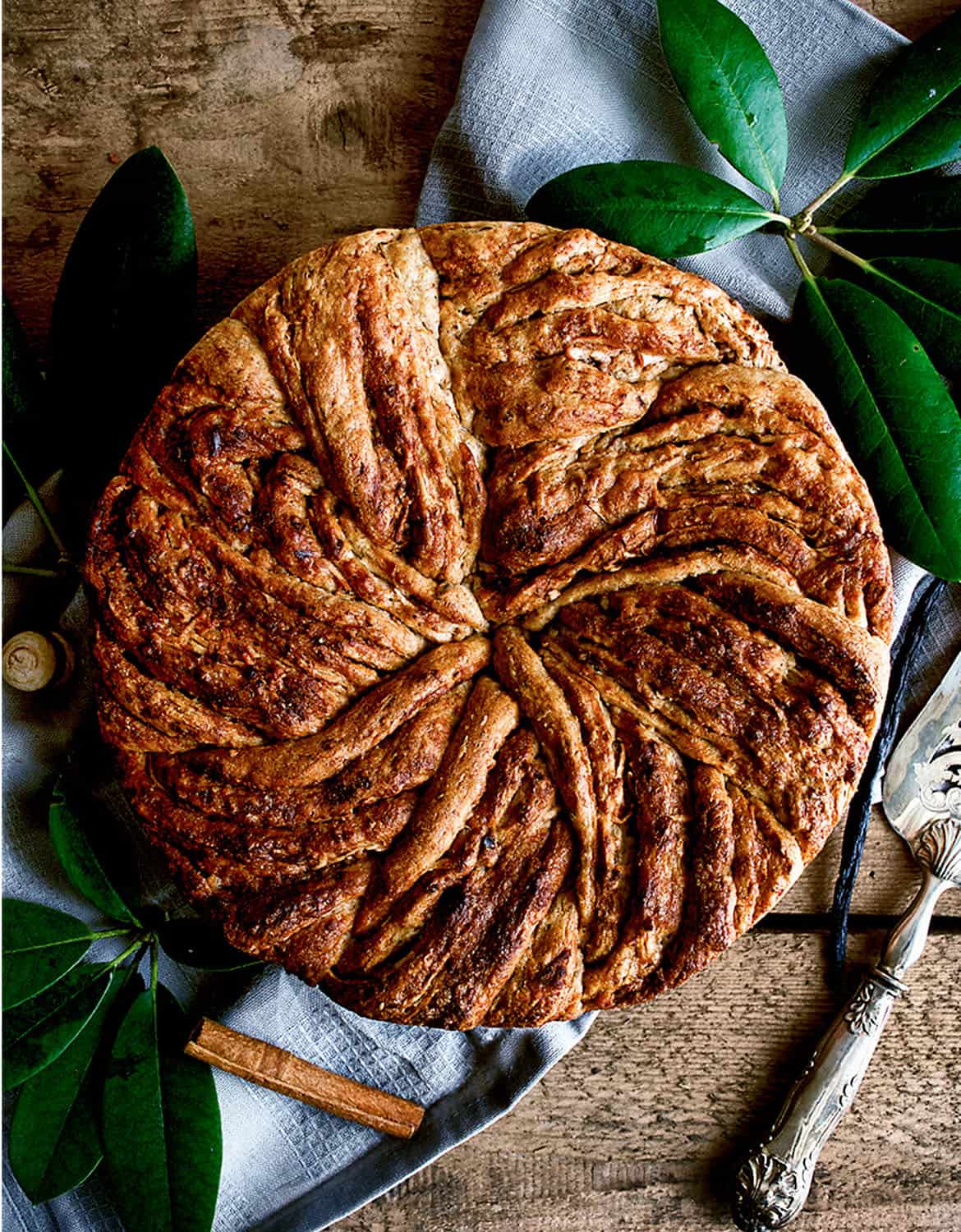 A round apple cinnamon bun cake over a rustic wooden table - Occasionally Eggs