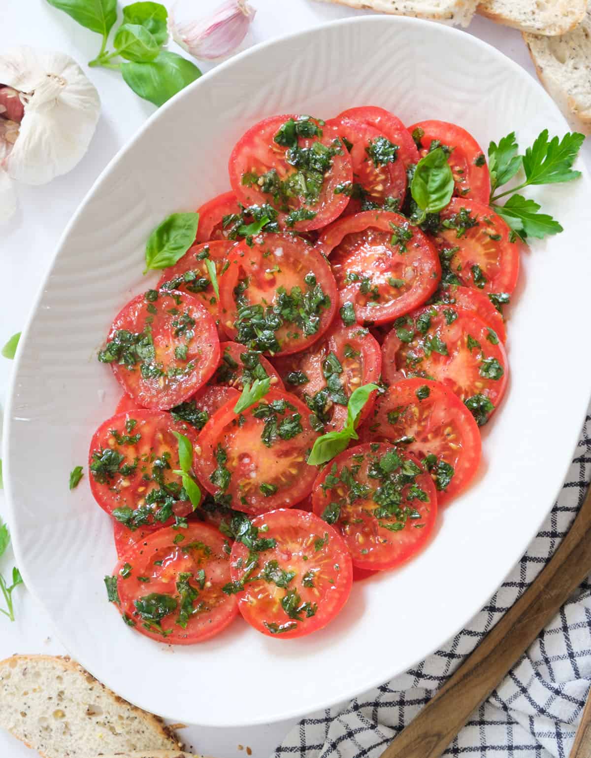 Top view of marinated tomato salad served on white salad plate.
