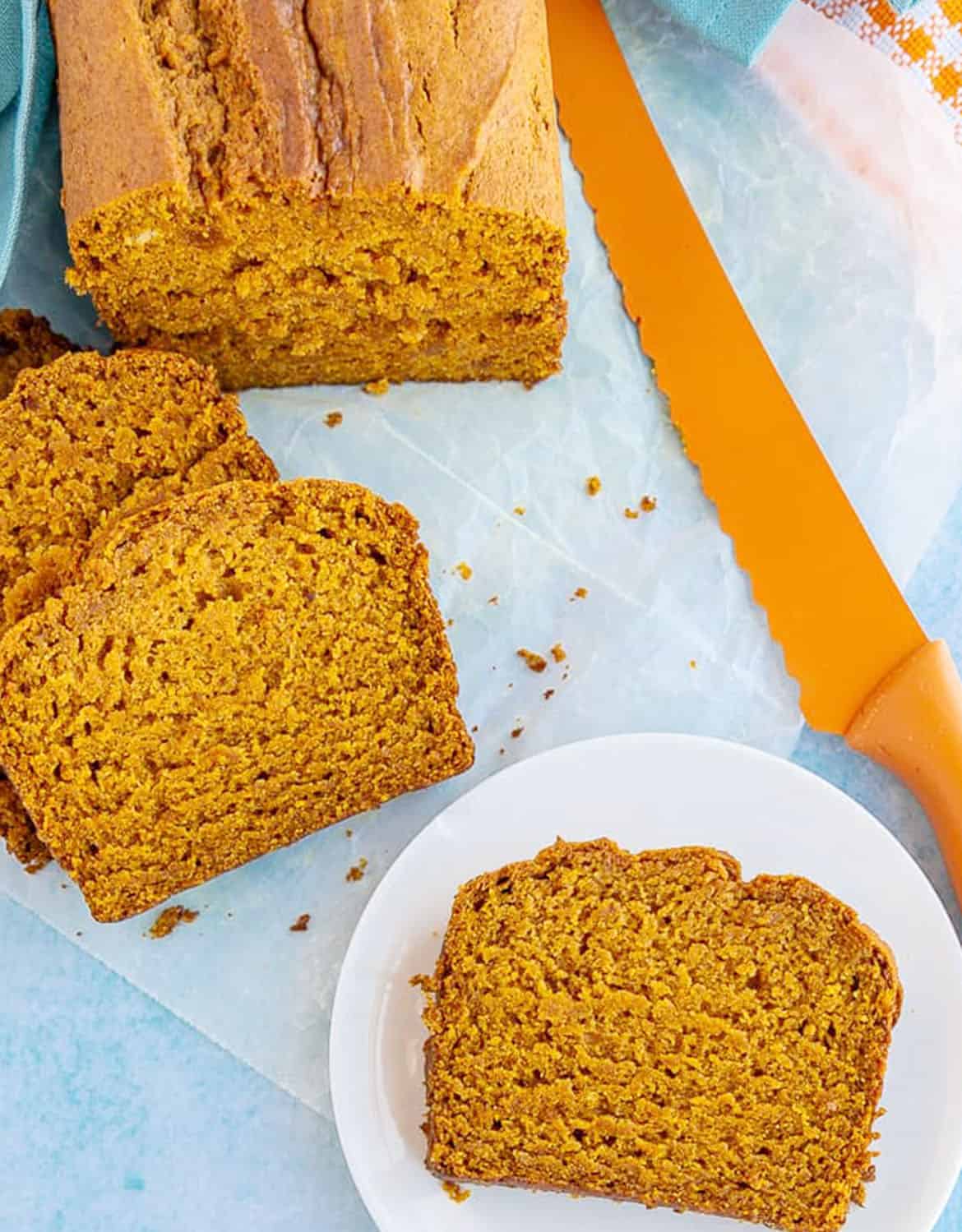 Vegan pumpkin bread cut into slices with an orange knife in the background - Love from The Oven