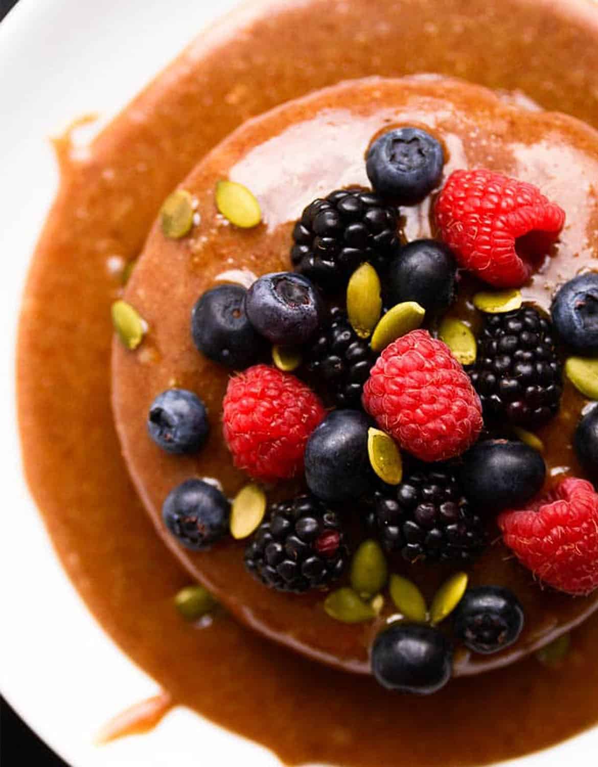 A round caramel cheesecake with mixed berries on top - Blissful basil