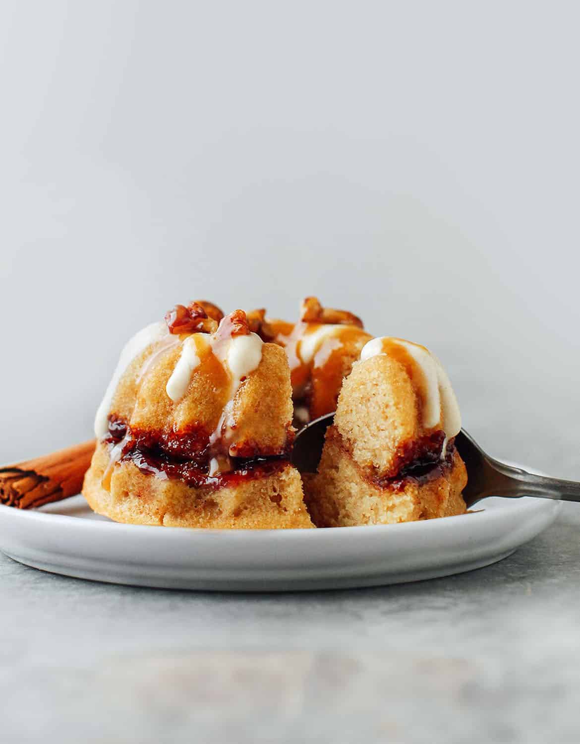 The mini cinnamon swirl bundt cake is on grey plate with a spoon - Full of Plants