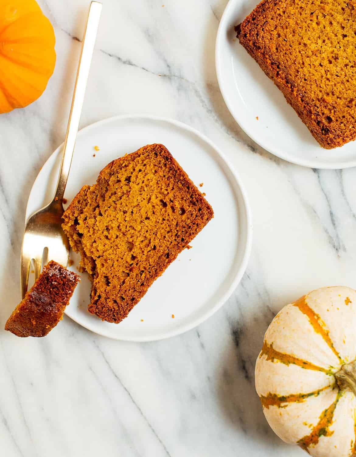 Two slices of healthy pumpkin bread on two small white plates - Cookie & Katie