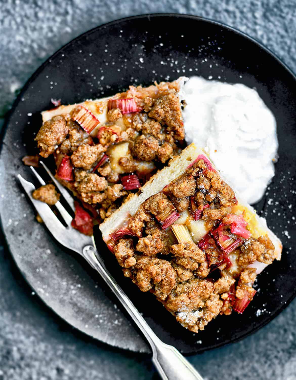 Vegan rhubarb streusel cake on a black plate with a fork - Occasionally Eggs