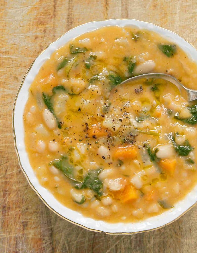 A top view of a white bowl full of white bean soup over a wooden background.