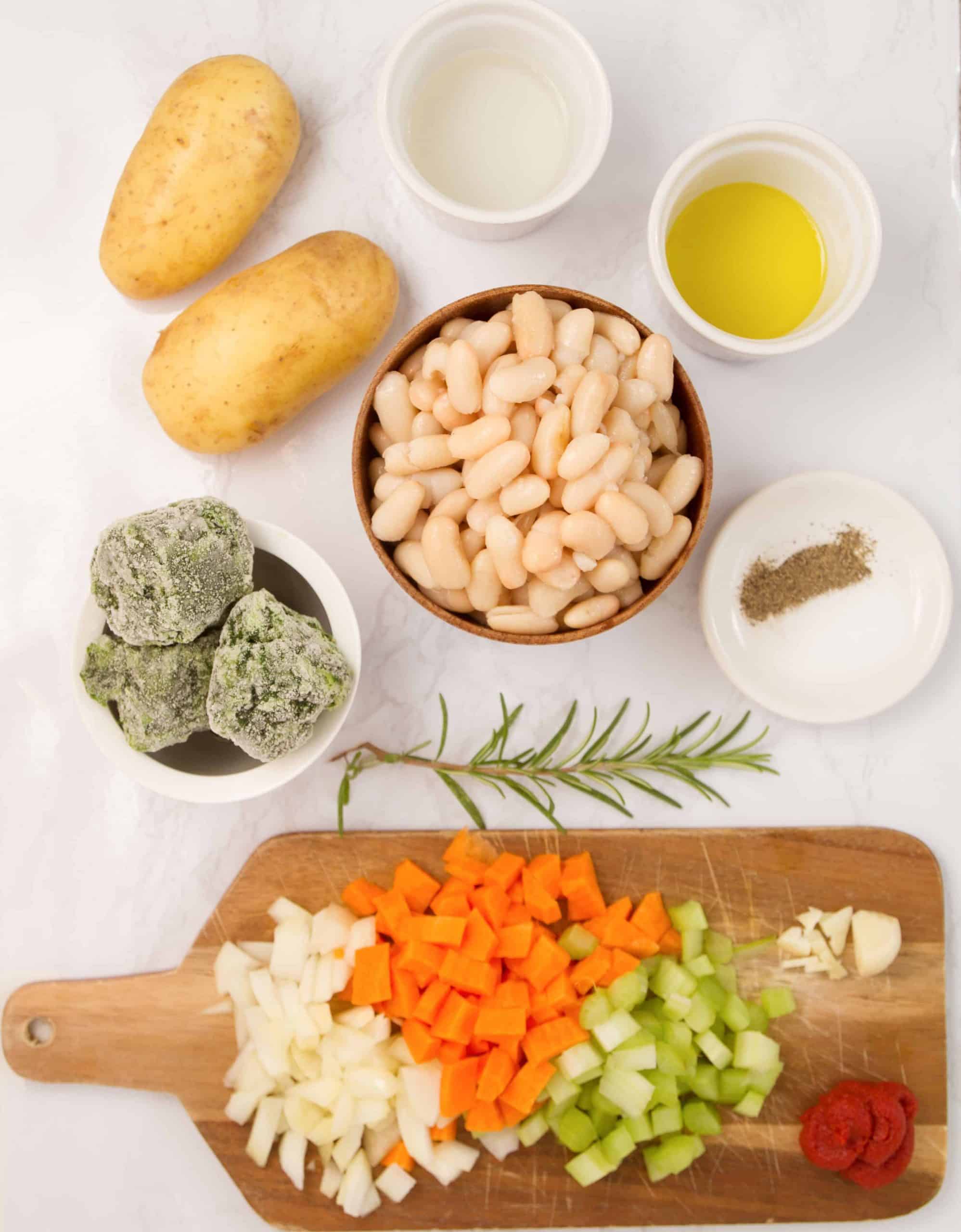 The ingredients for this white bean soup are arranged over a white table.