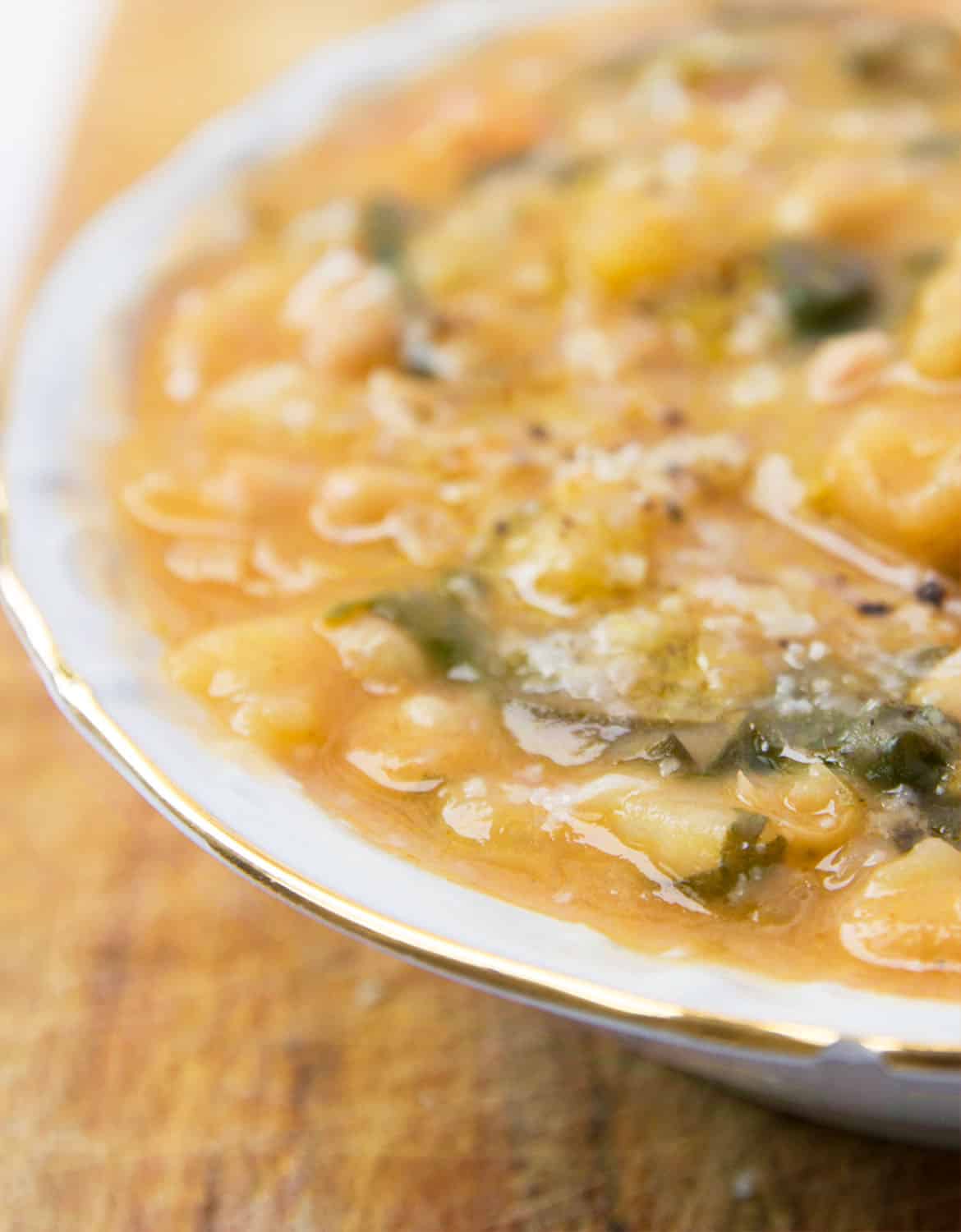 A close-up of the white bean soup over a wooden table.