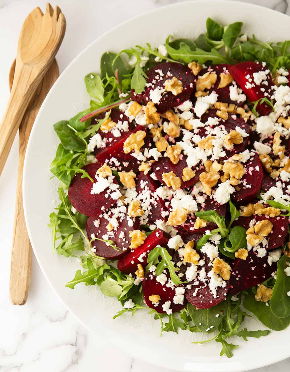 Beetroot salad with feta, arugula, and walnuts on a large white salad plate - The Clever Meal