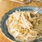 Delicious cream cheese pasta served on a blue bowl with a fork.