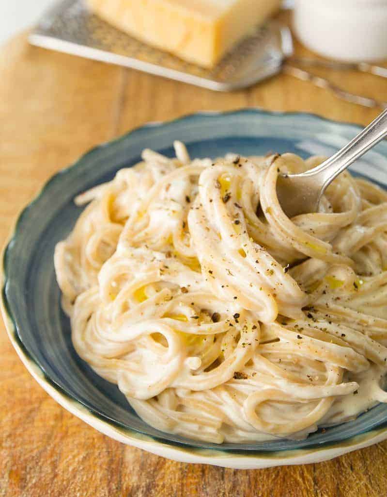 Delicious cream cheese pasta served on a blue bowl with a fork.