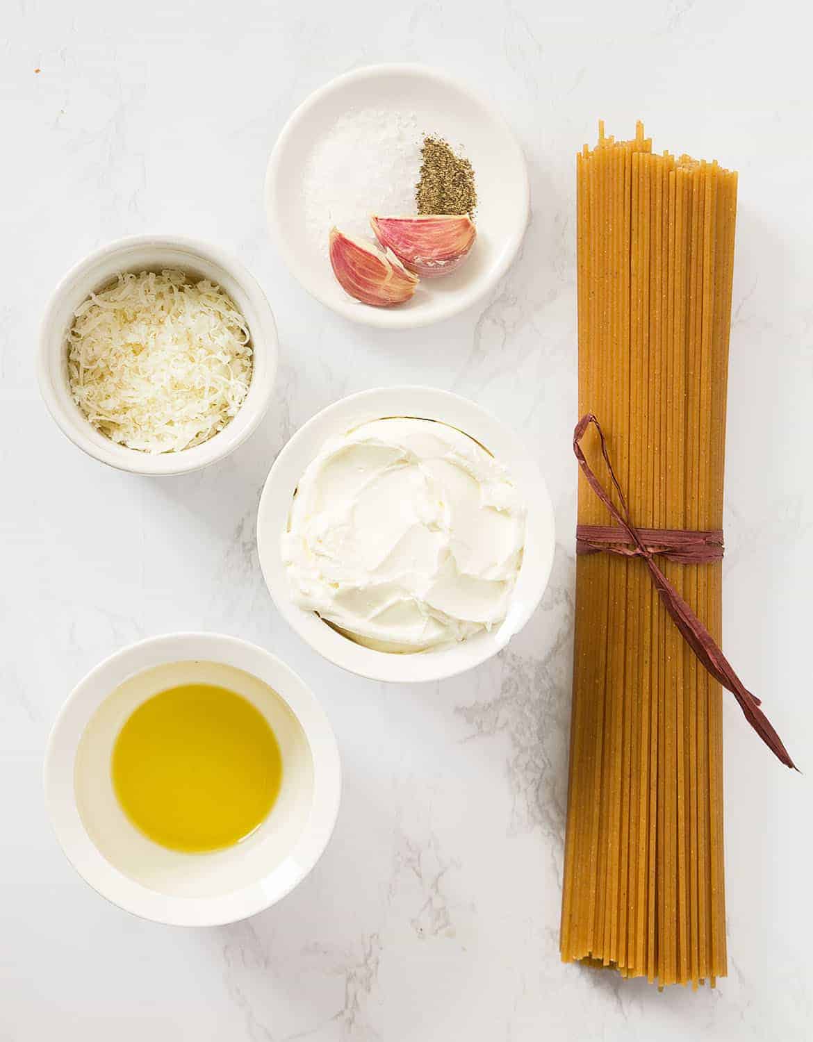 The ingredients to make this cream cheese pasta are arranged on a white table.