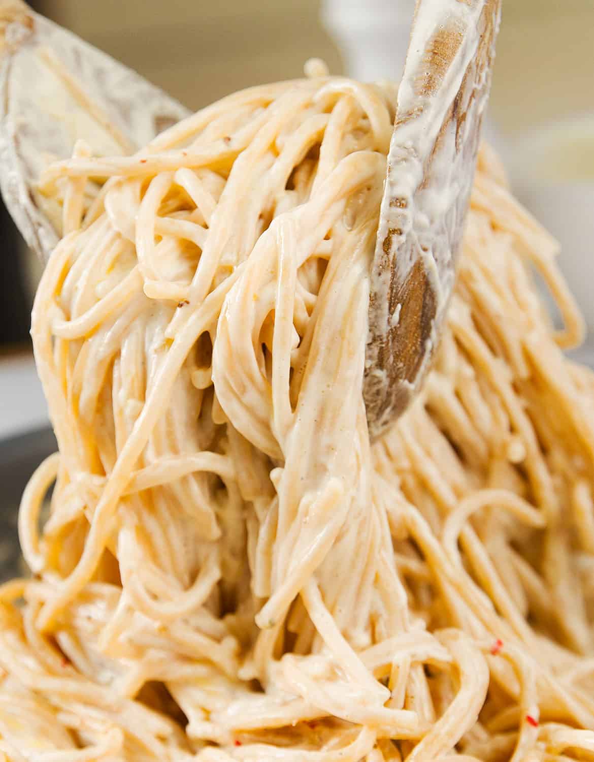 A portion of creamy cream cheese pasta and two wooden spoons.