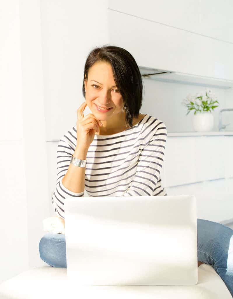 Katia, owner of The Clever Meal, sitting in front of laptop smiling.