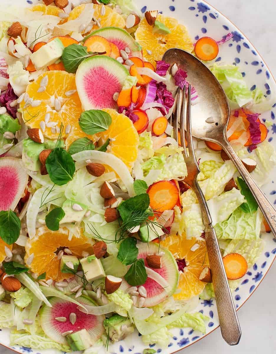 Cabbage salad with slice of oranges on a plate with a spoon and a fork - Love and Lemons