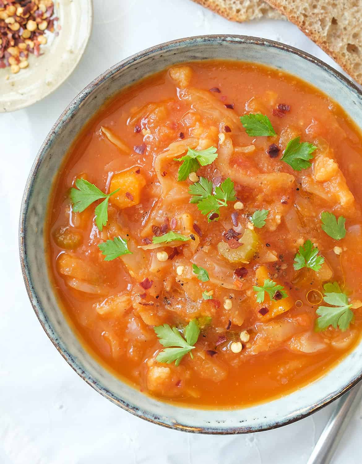 Cabbage soup with parsley leaves in a light blue bowl.