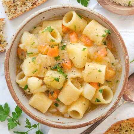 Top view of a bowl full of potato pasta served with crusty bread.