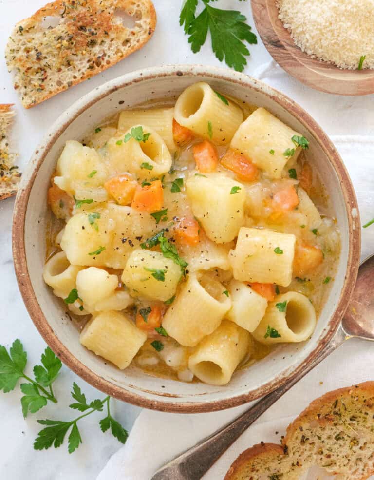 Top view of a bowl full of potato pasta served with crusty bread.